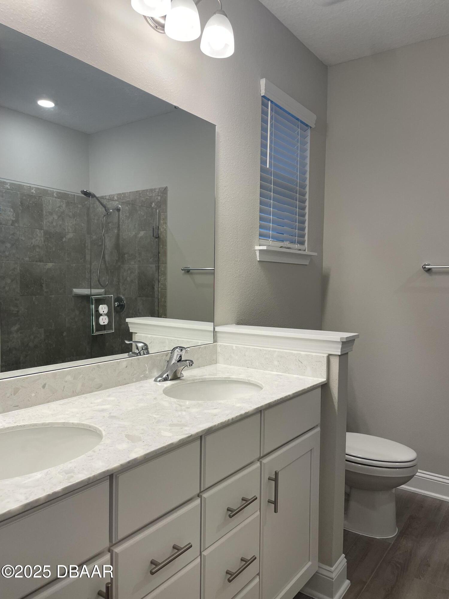 181 Thistleton Way St. Augustine, FL 32092 - Photo 27 of 31 a bathroom with a granite countertop sink a toilet and a mirror