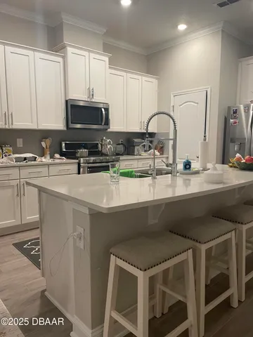 a kitchen with stainless steel appliances granite countertop a stove a sink a microwave a refrigerator and white cabinets