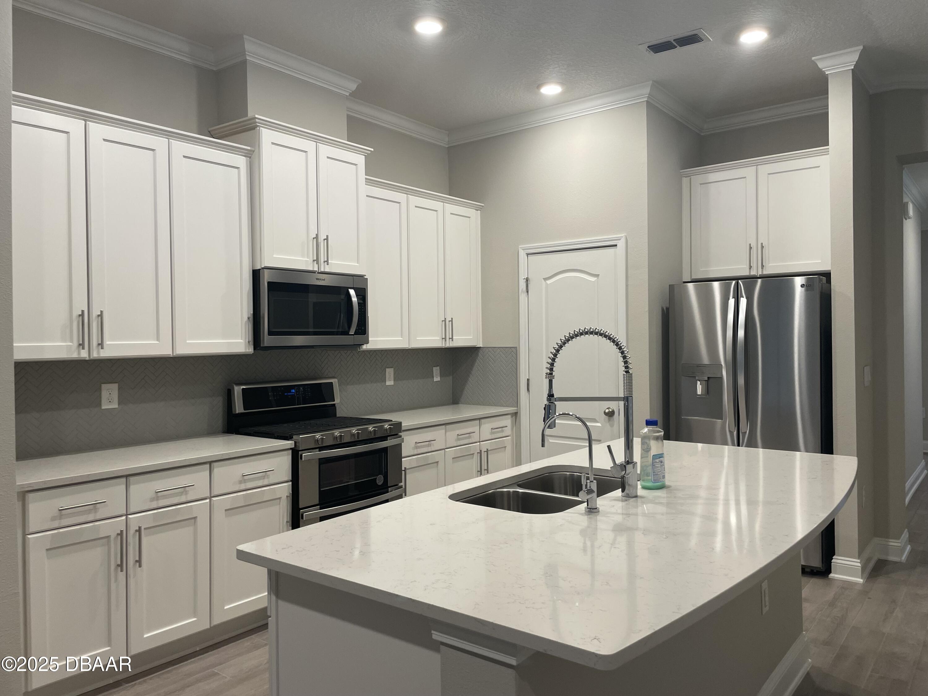 181 Thistleton Way St. Augustine, FL 32092 - Photo 9 of 31 a kitchen with white cabinets a sink and appliances