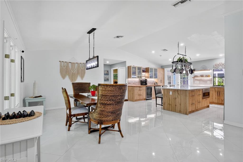 410 6th Street Northeast Naples, FL 34120 - Photo 13 of 32 Open and bright dining and kitchen area with vaulted ceilings and center kitchen island.