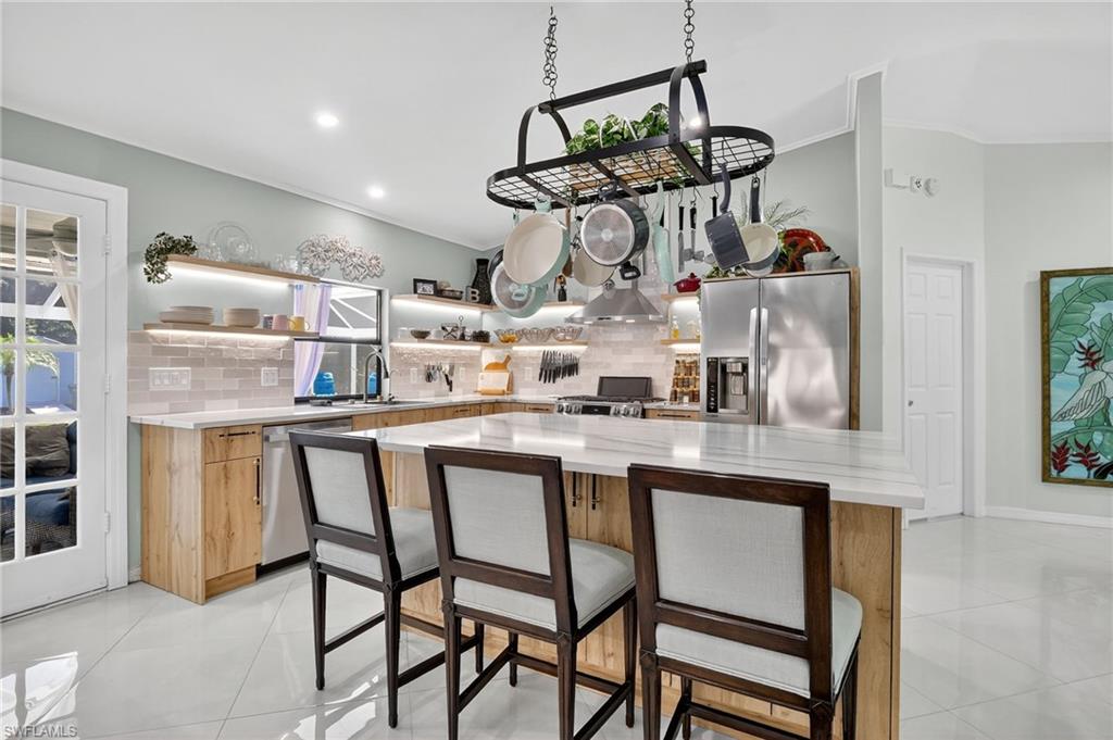 410 6th Street Northeast Naples, FL 34120 - Photo 16 of 32 Pan fixture and barstools are included in the kitchen.