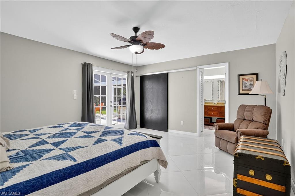 410 6th Street Northeast Naples, FL 34120 - Photo 24 of 32 Spacious master bedroom with room darkening curtains that stay, ceiling fan, access to exterior, ensuite bath and 2 separate closets.