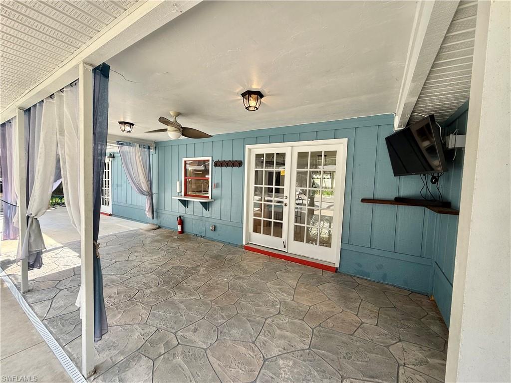410 6th Street Northeast Naples, FL 34120 - Photo 31 of 32 Covered back porch with outdoor TV, sliding window to kitchen.