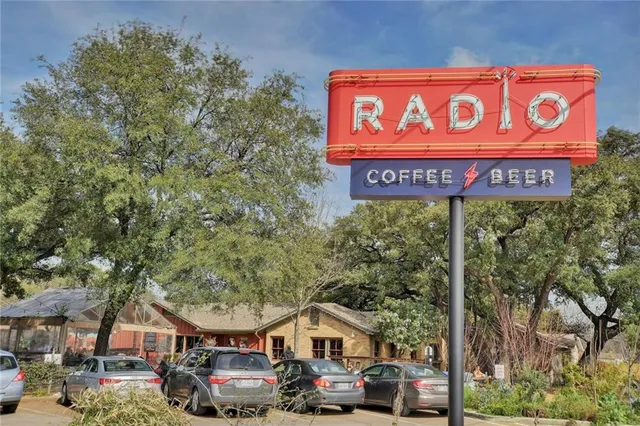 a view of a sign board with buildings and cars parked in front of it