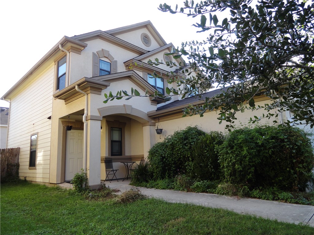 a view of a house with brick walls and a small yard with plants