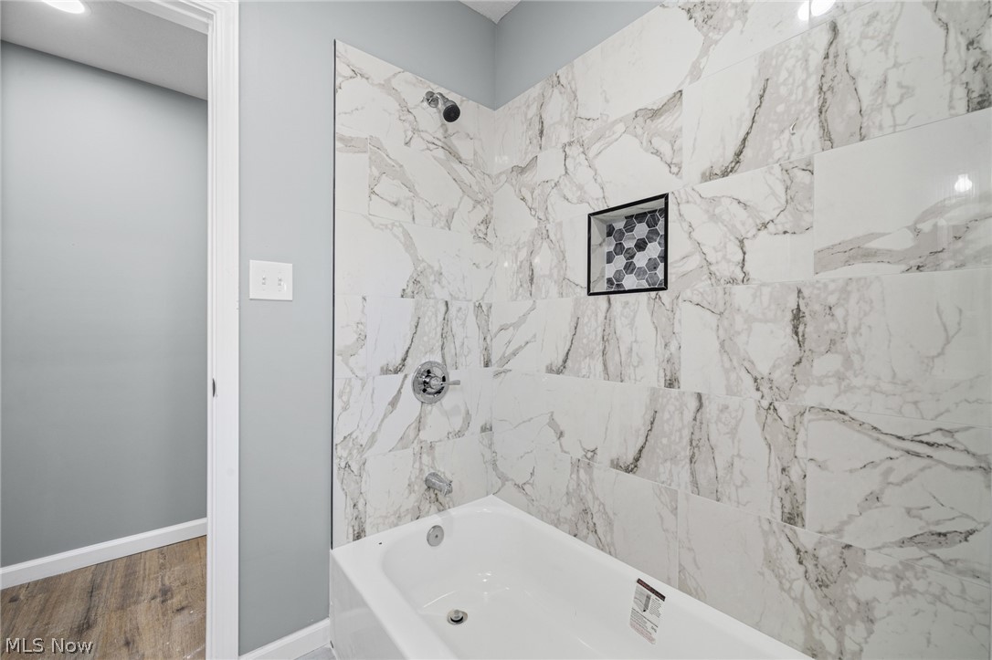 3925 Riverside Avenue Cleveland, OH 44109 - Photo 33 of 48 Bathtub with full-height marble-effect tile surround, featuring a recessed niche with mosaic tile accent
