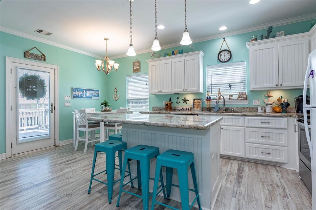 987 Surf Crystal Beach Crystal Beach, TX 77650 - Photo 11 of 45 a kitchen with granite countertop a table chairs stove and cabinets