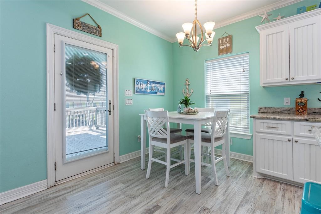 987 Surf Crystal Beach Crystal Beach, TX 77650 - Photo 7 of 45 a dining room with wooden floor a chandelier a wooden table and chairs