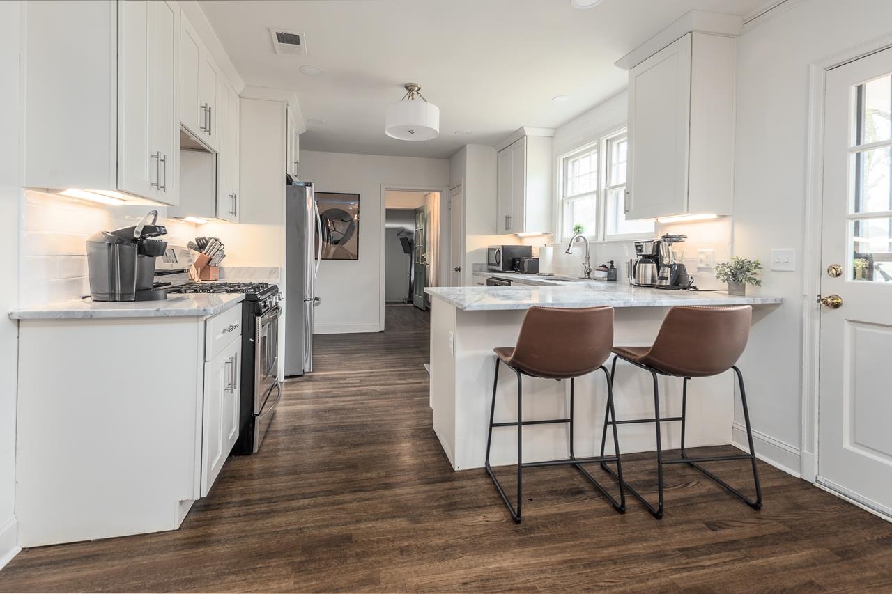 8 South Ashlawn Road Memphis, TN 38112 - Photo 4 of 23 a kitchen with stainless steel appliances granite countertop a table chairs stove and white cabinets