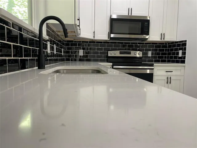 a kitchen with a sink a microwave and cabinets