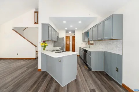 a kitchen with a sink cabinets wooden floor and stainless steel appliances