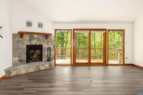 a view of an empty room with wooden floor and a fireplace