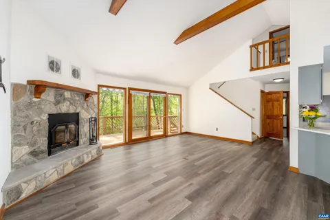 a view of an empty room with wooden floor fireplace and a window