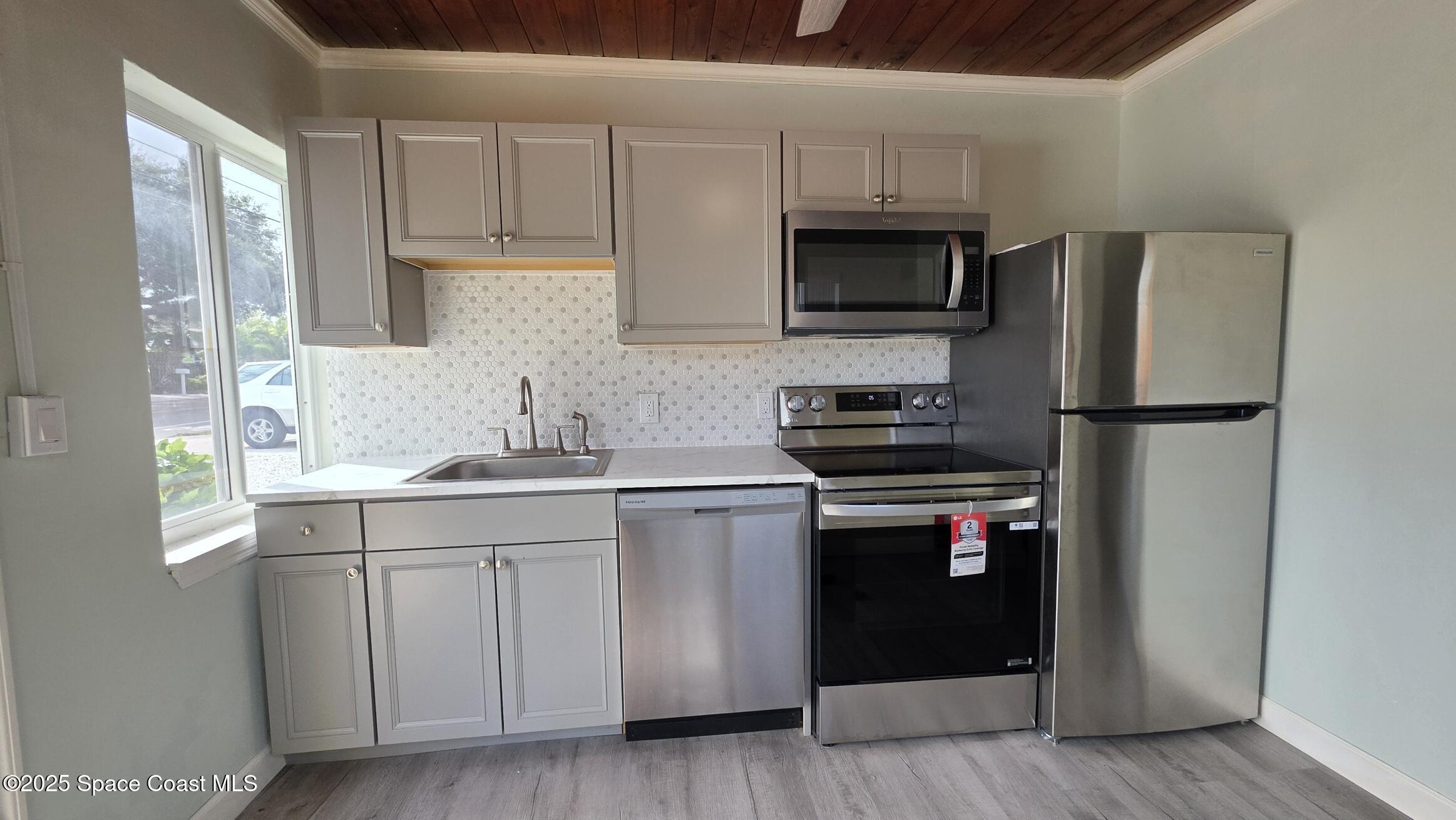 6411 Ridgewood Avenue Cocoa Beach, FL 32931 - Photo 2 of 15 a kitchen with a sink stainless steel appliances and cabinets