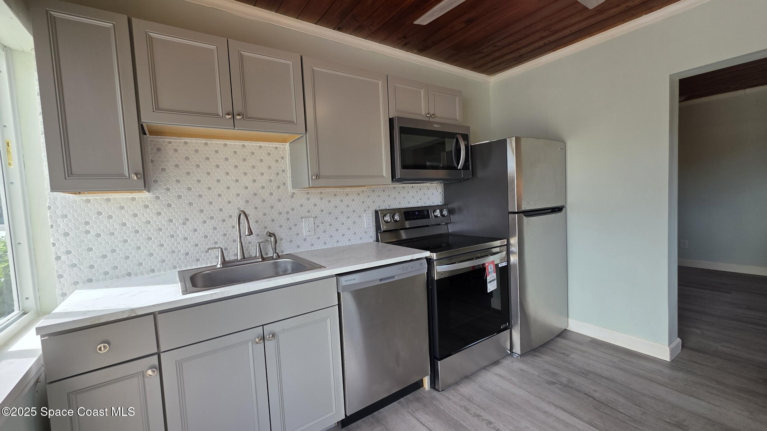 6411 Ridgewood Avenue Cocoa Beach, FL 32931 - Photo 3 of 15 a kitchen with stainless steel appliances granite countertop a sink a stove a microwave and cabinets