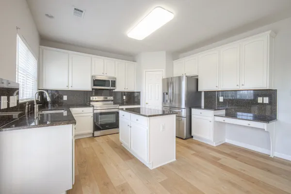 a kitchen with granite countertop a sink and white cabinets
