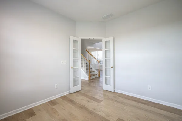an empty room with wooden floor fan and windows