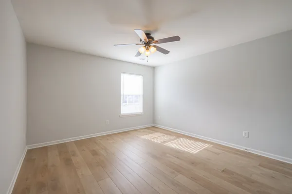 an empty room with a window and a fan