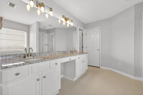 a bathroom with a granite countertop sink a large mirror a and a window