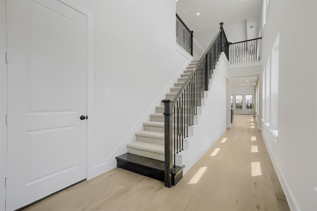 824 Stone Grv Road Lavon, TX 75166 - Photo 2 of 26 Elegant staircase featuring dark wood newel posts, black metal balusters, and carpeted treads