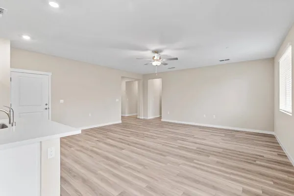 a view of an empty room with wooden floor and chandelier