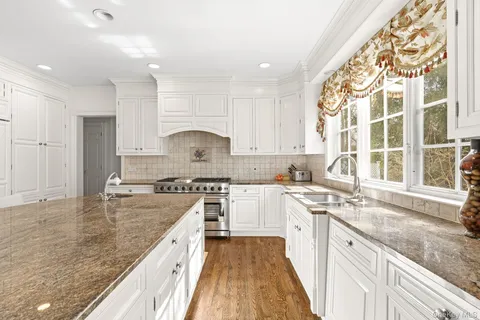 a large kitchen with kitchen island a large counter space a sink stainless steel appliances and cabinets