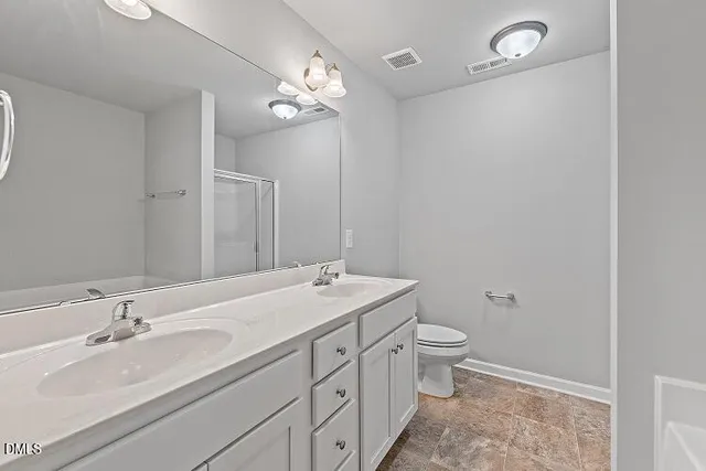a bathroom with a double vanity sink mirror and toilet