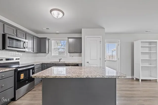 a kitchen with granite countertop a sink a stove and cabinets