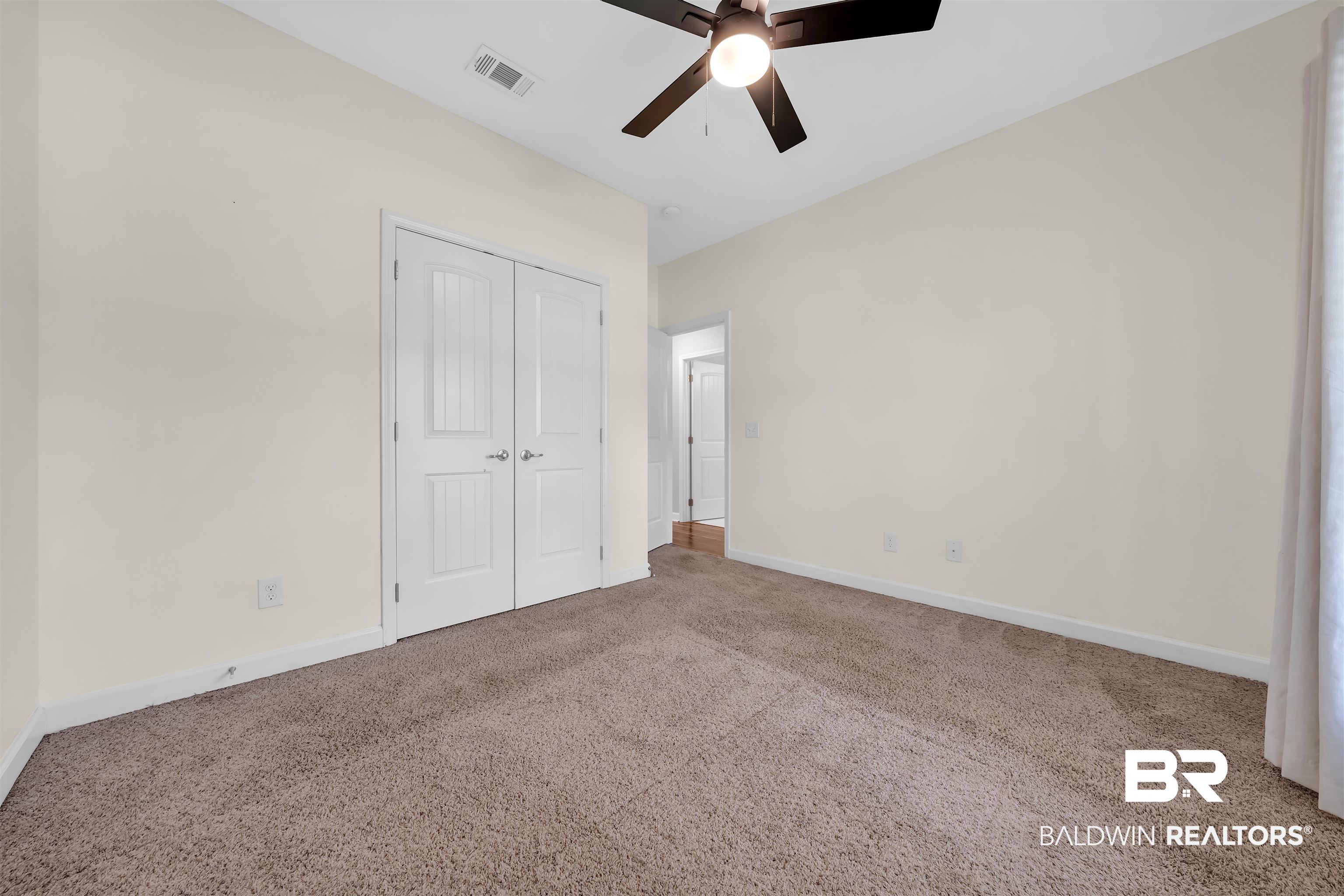 10147 Lyttleton Loop Lillian, AL 36549 - Photo 26 of 29 Spacious room featuring neutral wall tones, plush carpeting, a modern ceiling fan, and white double doors