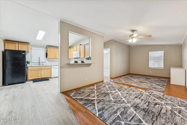 a view of kitchen and empty room with wooden floor