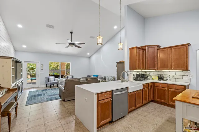 a large kitchen with stainless steel appliances kitchen island granite countertop a stove top oven a sink dishwasher a dining table and chairs with wooden floor
