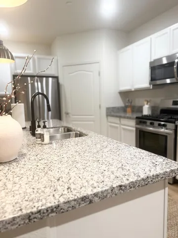 a kitchen with granite countertop a sink and a stove top oven with wooden floor
