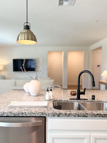 a kitchen with granite countertop a stove a sink and a wooden floor