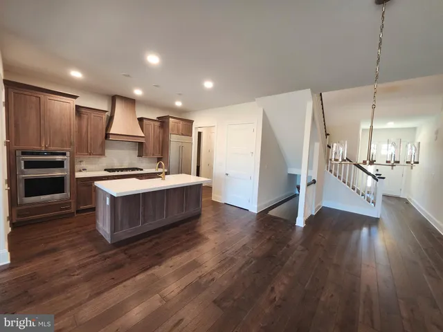 a large kitchen with a center island wooden floor stainless steel appliances and a window