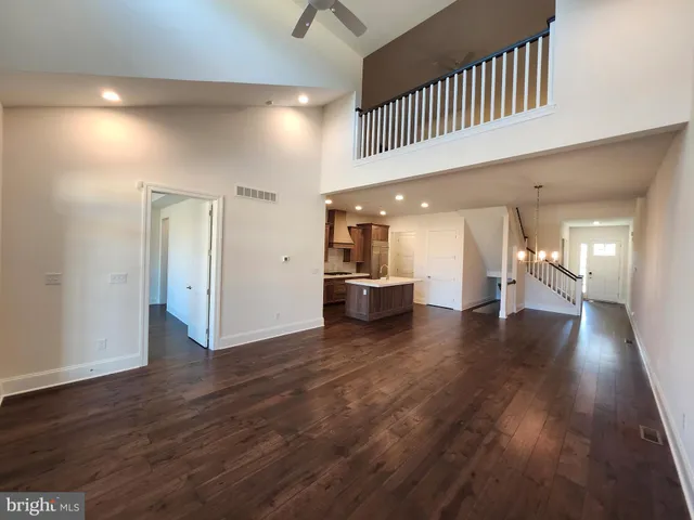 a view of a hallway with wooden floor and a kitchen