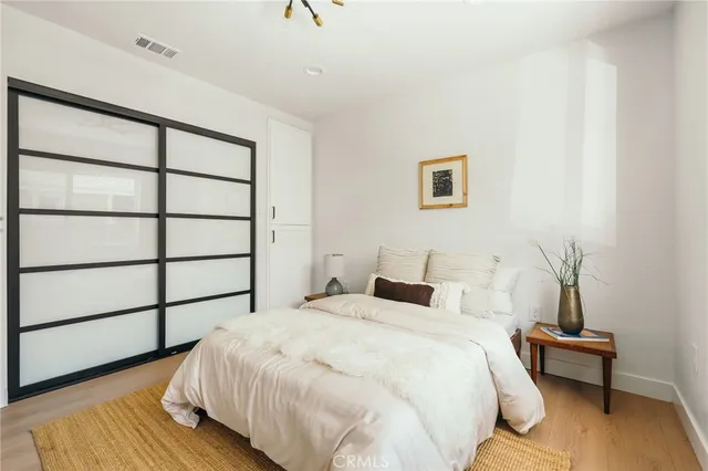 a view of a hallway with wooden floor and a bathroom
