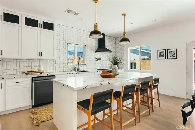 a large kitchen with stainless steel appliances kitchen island granite countertop a stove a sink a dining table and chairs with wooden floor