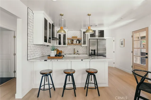 a kitchen with stainless steel appliances kitchen island granite countertop a table chairs in it and white cabinets
