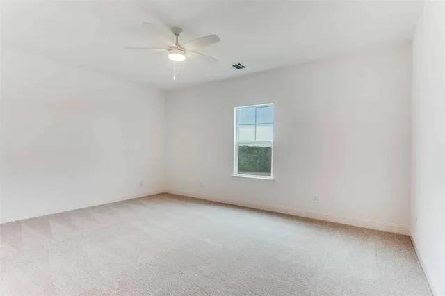 an empty room with a ceiling fan and windows