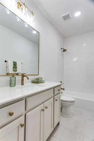 a bathroom with a double vanity sink toilet and a tub