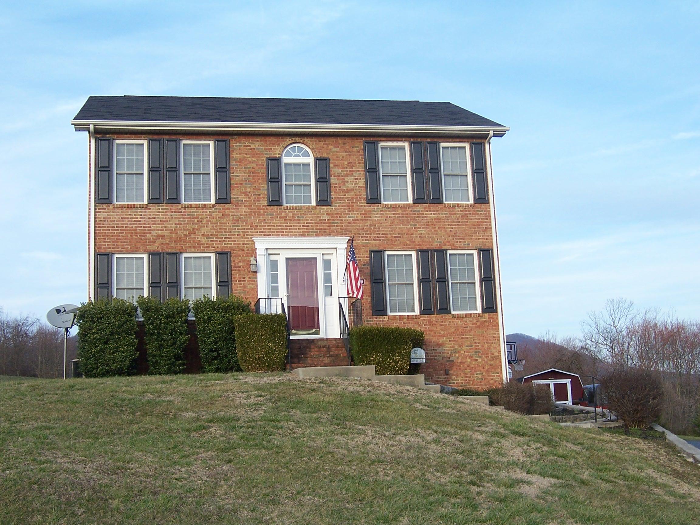 a front view of house with yard and trees in the background