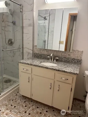 a bathroom with a granite countertop sink a mirror and shower