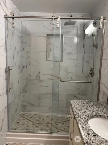 a bathroom with a granite countertop shower and a sink