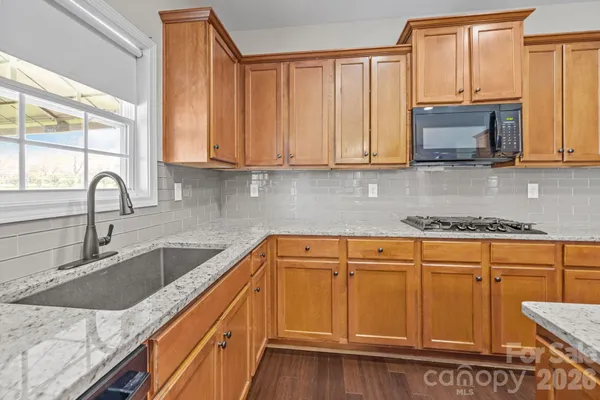a kitchen with granite countertop a sink a stove and cabinets