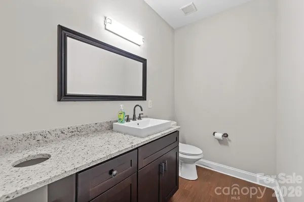a bathroom with a granite countertop toilet sink and mirror