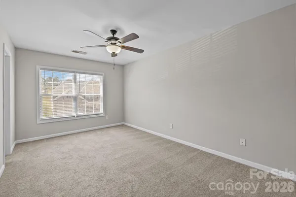 an empty room with windows and fan