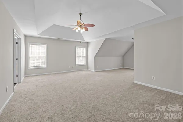 an empty room with windows and chandelier fan