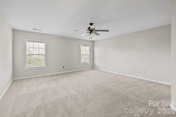 an empty room with windows and ceiling fan
