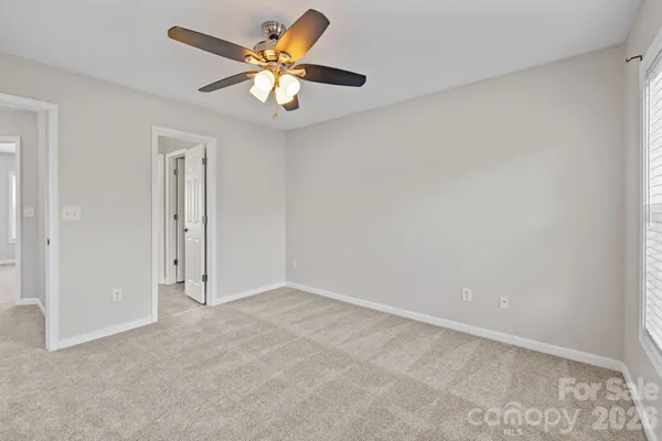 an empty room with a chandelier fan and a window