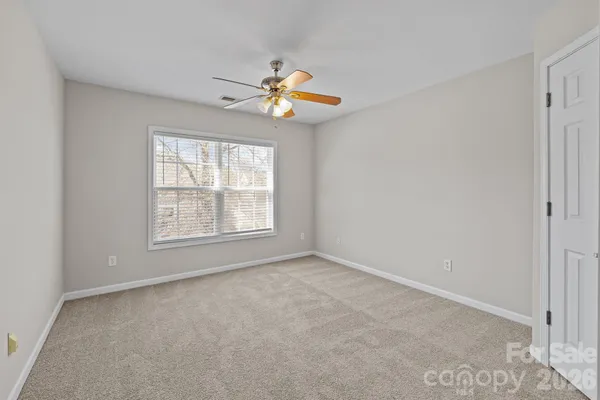 an empty room with windows and chandelier fan